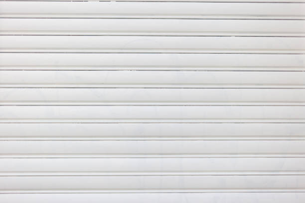 Modern empty white color roller shutter door background texture. Metal garage door construction, closed foldable entrance, safety. Copy space