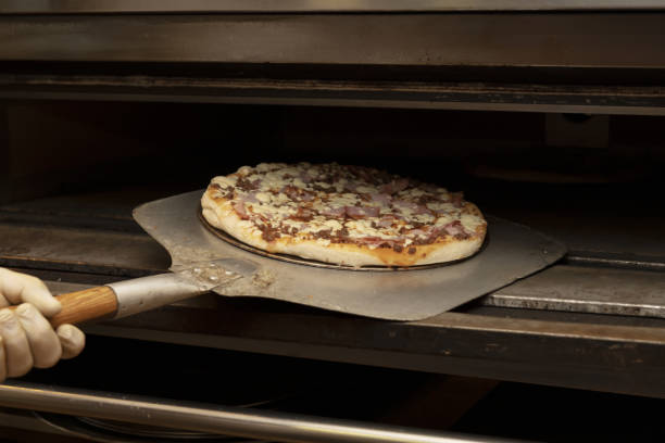 istock A pizza maker flipping a pizza with a shovel inside 1481743287