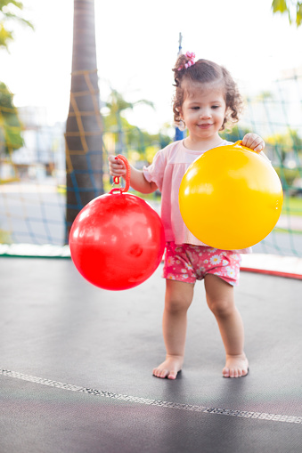 beautiful cheerful child playing on the playground. holding balls in red and yellow colors