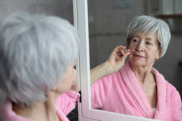 Senior woman plucking nose hairs stock photo