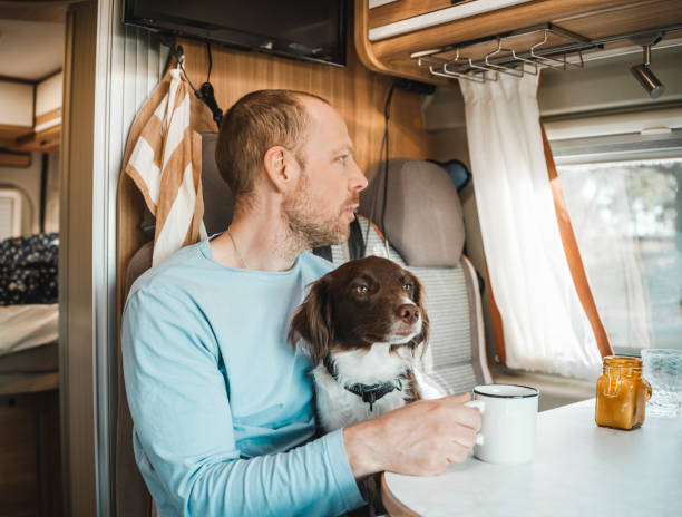 istock Man and his dog in a camper van drinking coffee out on adventure 1481749588