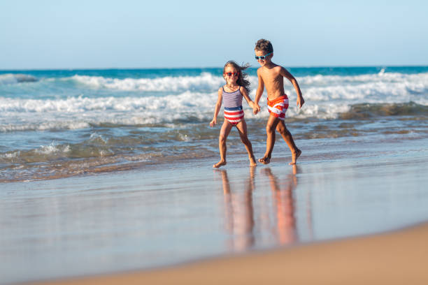 Cheerful children running together on a beautiful beach, having fun on their summer vacation
