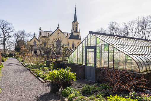 Garden with a neo-Gothic cruciform church in the background in the small Dutch village of Neerijnen in the Betuwe.