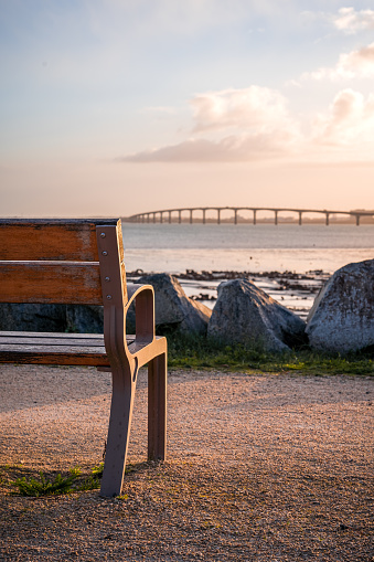 Isolated and empty public bench at sunrise. Bridge of the island of Re in background. peaceful or zen concept