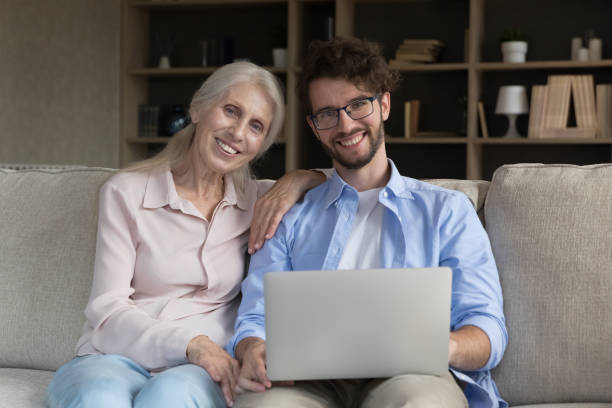 istock Cheerful smart young man helping with computer to senior mom 1481755833