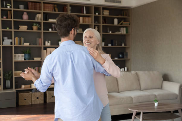 Happy different aged couple training social dance, waltz, tango Happy different aged couple training social dance, waltz, tango. Adult son and older senior mom enjoying active hobby together, dancing to music, holding hands, spinning teacher retirement party stock pictures, royalty-free photos & images