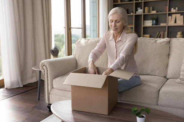istock Positive older customer lady receiving parcel, opening cardboard box 1481755903