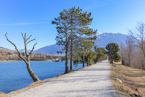 A scenics view of the Embrun, France lake path with snowy mountains range in the background under a majestic blue sky