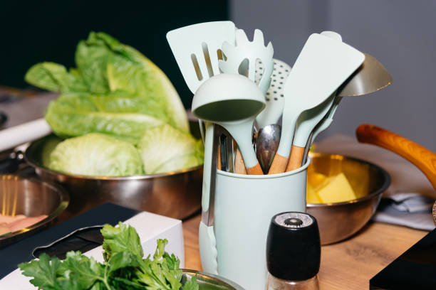 istock Kitchen utensils on a table in the kitchen. Raw ingredients, bowl with salad leaves, bowl with butter. Plastic spatulas, skimmers, and ladles. 1481756055