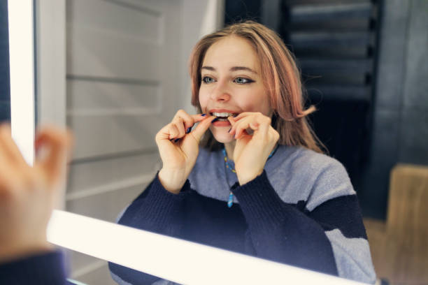 девочка-подросток надевает прозрачный зубной элайнер в ванной комнате - health care healthcare and medicine contemporary satisfaction стоковые фото и изображения
