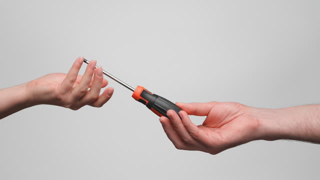Man is giving black and orange screwdriver to a woman. Close up, slow motion, 4k.