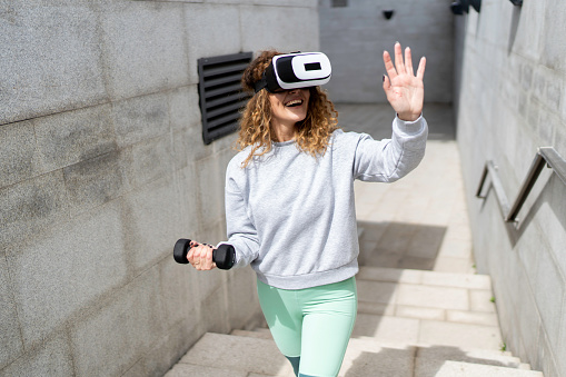 Fit young Caucasian woman wearing virtual reality goggles during sports exercise