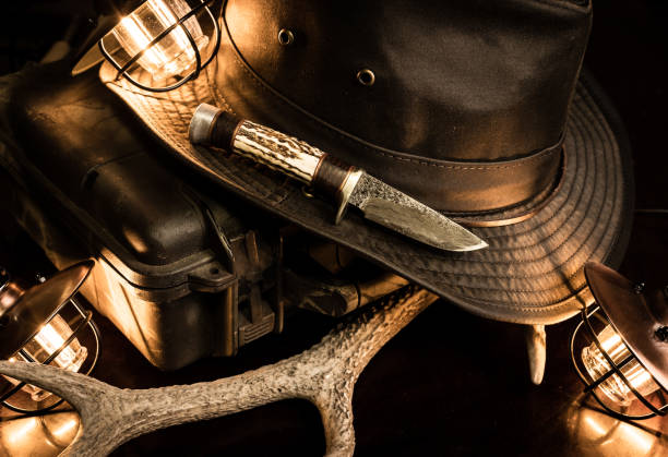 A still life of old vintage style gear displayed with antique lights, cowboy hat and custom hunting knife with deer antler.