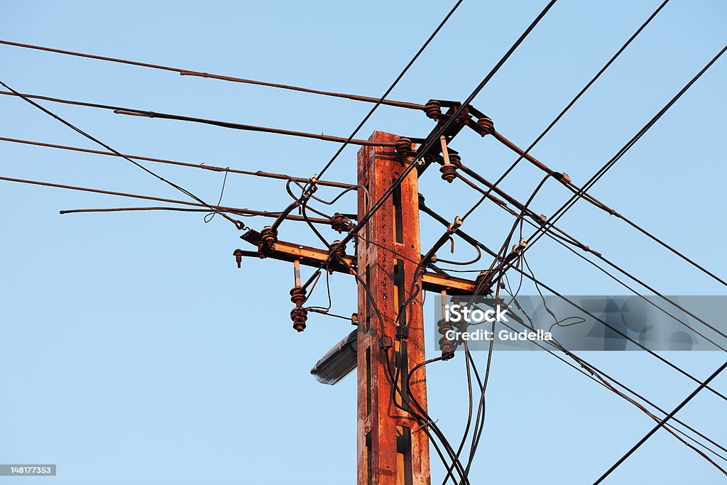 Electric Line Old, rusty electric line against blue sky Architectural Column Stock Photo