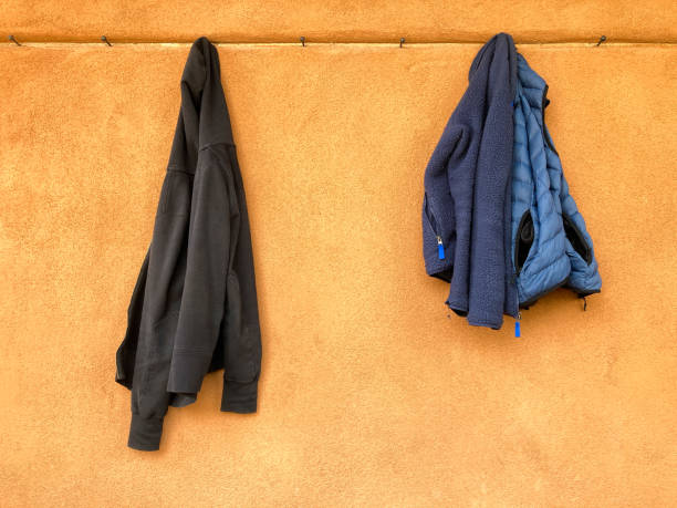 istock Two Jackets Hanging on Pegs on Orange Wall 1481778726