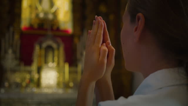 Christian woman folded hands in prayer in church.