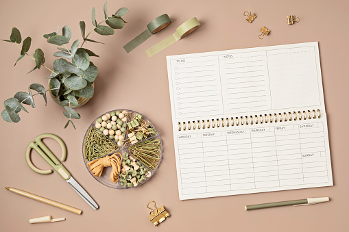 Mockup of  weekly planner and coffee cup on beige  background, with copy space for text. Flat lay, top view photo mock up.