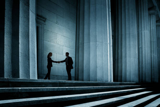 Man And Woman Shake Hands In The Shadows stock photo