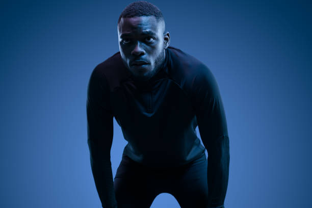 istock Young black sportsman leaning forward in blue studio 1481789287