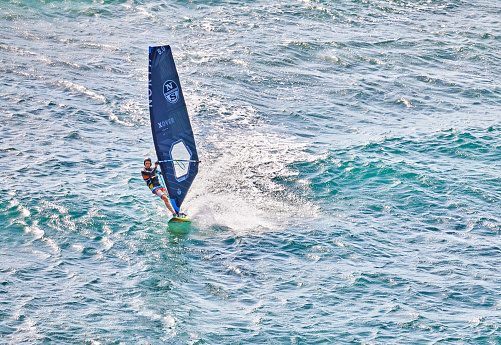 Honolulu, Oahu, Hawaii, USA, - February 6, 2023: A Windsurfer in the Ocean surfing the Waves