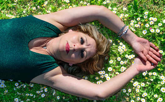 Mature woman lying in grass with marguerite. Menopause and mother's day concept