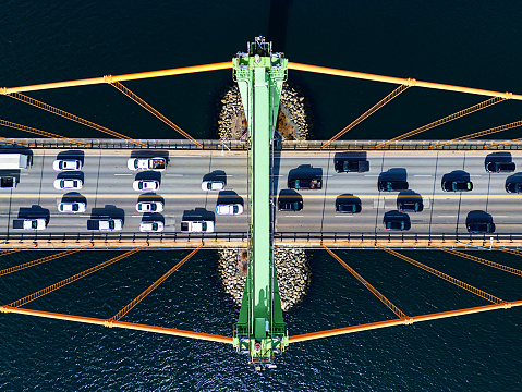 Crowded white and black traffic on a suspension bridge at rush hour.