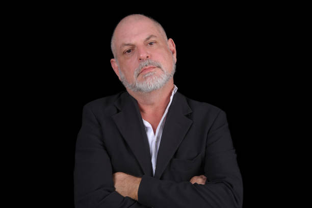 istock Handsome middle-aged man in a suit posing against black background. confident business man 1481812803
