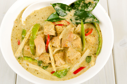 Traditional Thai green chicken curry with bamboo shoots and green beans, garnished with red chillies and kaffir lime leaves.