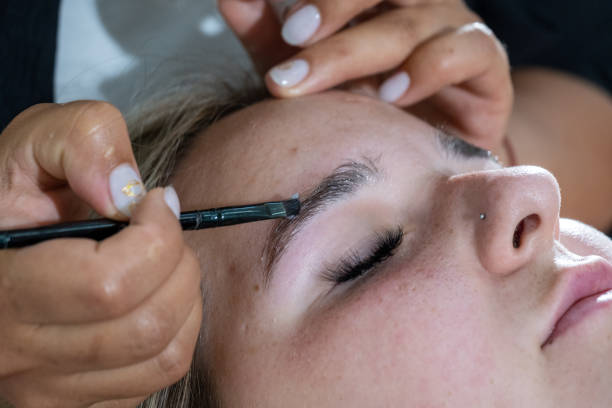 Makeup artist laminates woman eyebrows before tinting
