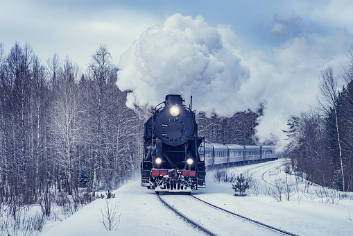 Retro steam train moves at winter morning time.