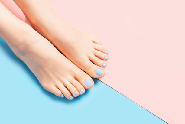 Female legs with pedicure on pink and blue background, copy space. stock photo