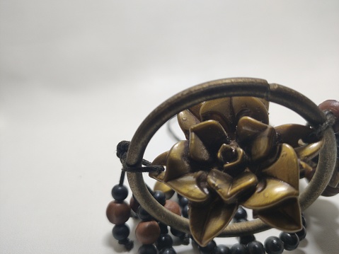 personal accessory, intricate and antique necklace, with a string of black beads, there are some brown natural stone ornaments, and a moon pendant in the center is a bronze rose shape