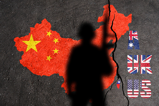 China and Taiwan flag map painted on a concrete wall with soldier shadow. Aukus is a trilateral security pact between Australia, the United Kingdom, and the United States. Relations between AUKUS and China