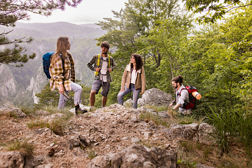 Group of young backpackers talking while taking a break during rainy day on a mountain.