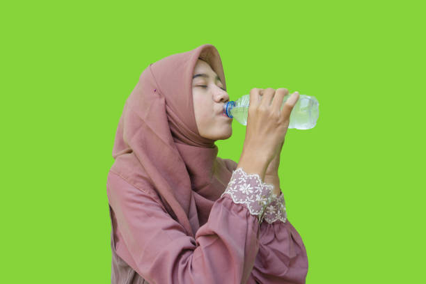 istock Muslim woman drinking bottled water with green background 1481829088