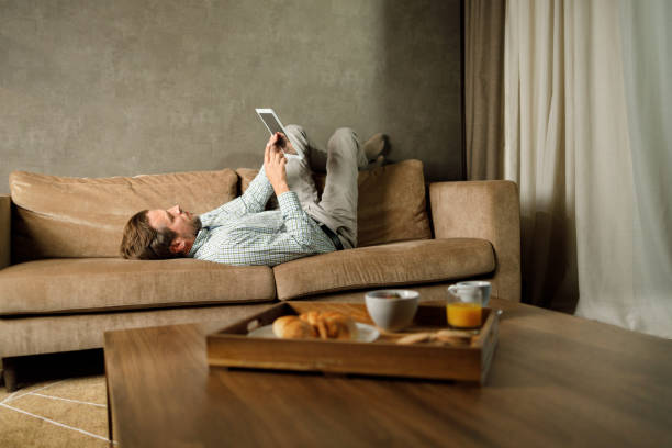 istock Relaxed mid adult entrepreneur using digital tablet on sofa at home. 1481829099