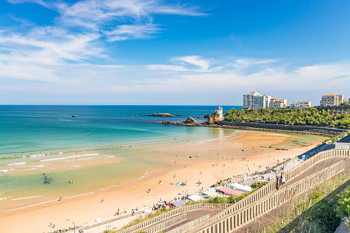 Surfers on the sand of Cote des Basques beach in Biarritz with surf school tents set up along the seaside in France