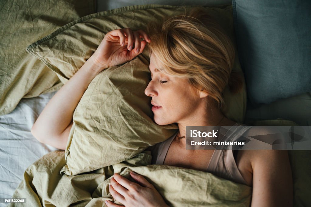Top View of Woman Sleeping in Bed Top view of a beautiful blonde woman sleeping in bed. She looks peaceful and fast asleep. Sleeping Stock Photo
