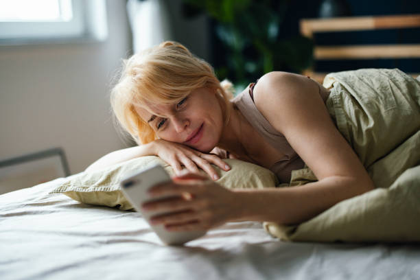 istock Beautiful Woman Lying in Bed and Using Mobile Phone 1481832282