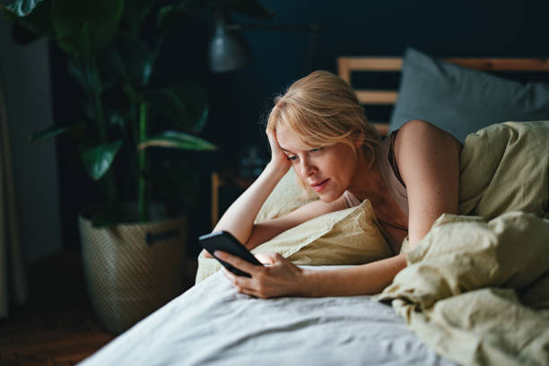 istock Smiling Woman Using A Mobile Phone In The Bedroom 1481832300