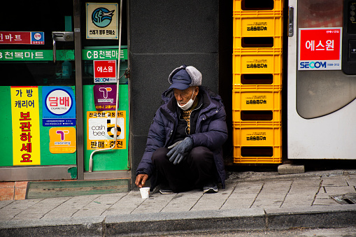 Life and lifestyle of old korean men beggar sitting and begging money from travelers people travel visit Gamcheon Culture Village or Santorini of Pusan city on February 18, 2023 at Busan, South Korea
