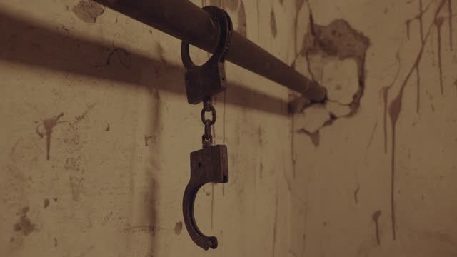 The handcuffs chained to a pipe in an old abandoned building or horror house
