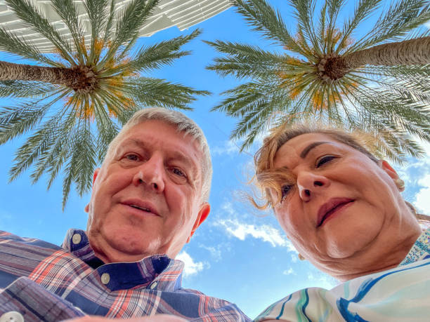 Senior mixed ethnicity couple close portrait palm trees