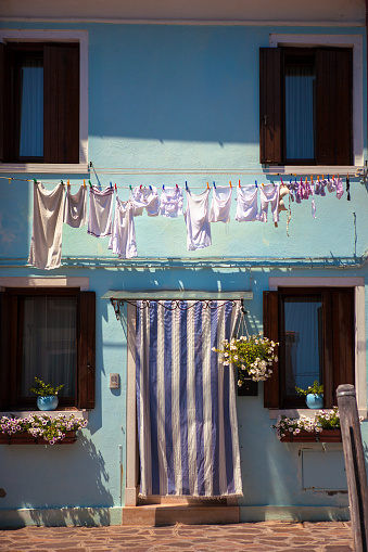 Pale blue two storey cottage with sun awning over the front door and washing hanging out to dry above: Fondamenta Pontinello Sinistra, Burano, Venice, Italy