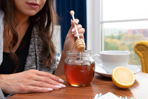 istock Sick woman putting some honey in her tea 1481843403