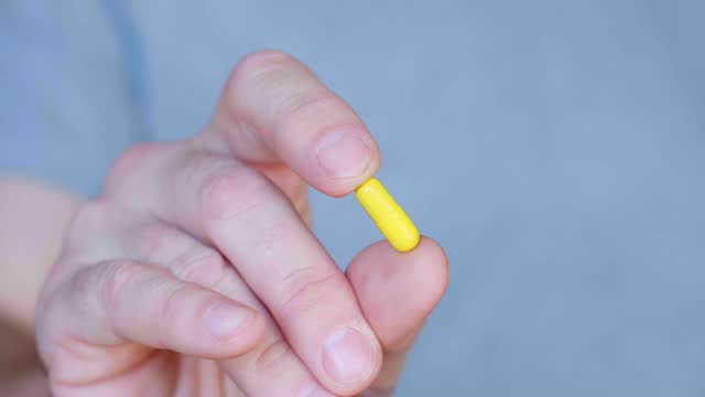 Yellow capsule in a human hands.