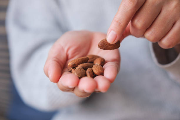 istock Closeup image of hands holding and picking up an almonds 1481843929