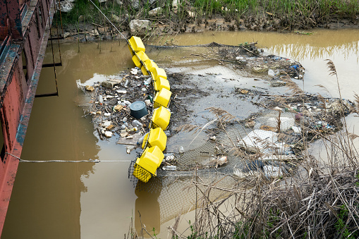 Cleaning water of stream flowing into sea with net for collecting floating debris