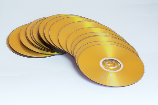 Group of gold colored compact discs on a white background