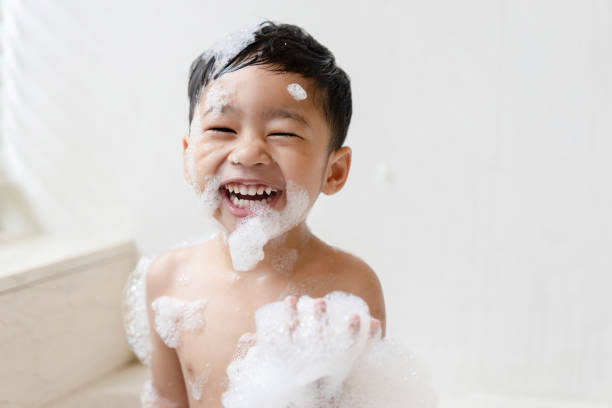 garçon prenant un bain dans la baignoire prendre un bain il joue avec des bulles - bath england photos et images de collection